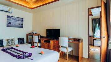 Habitación de hotel con cama, escritorio, televisión y vista al mar por la ventana.