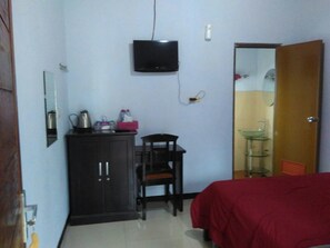 A small room with a bed, a desk with a chair, a television mounted on the wall, and a wardrobe. - Jazzi Homestay (Wonokitri)