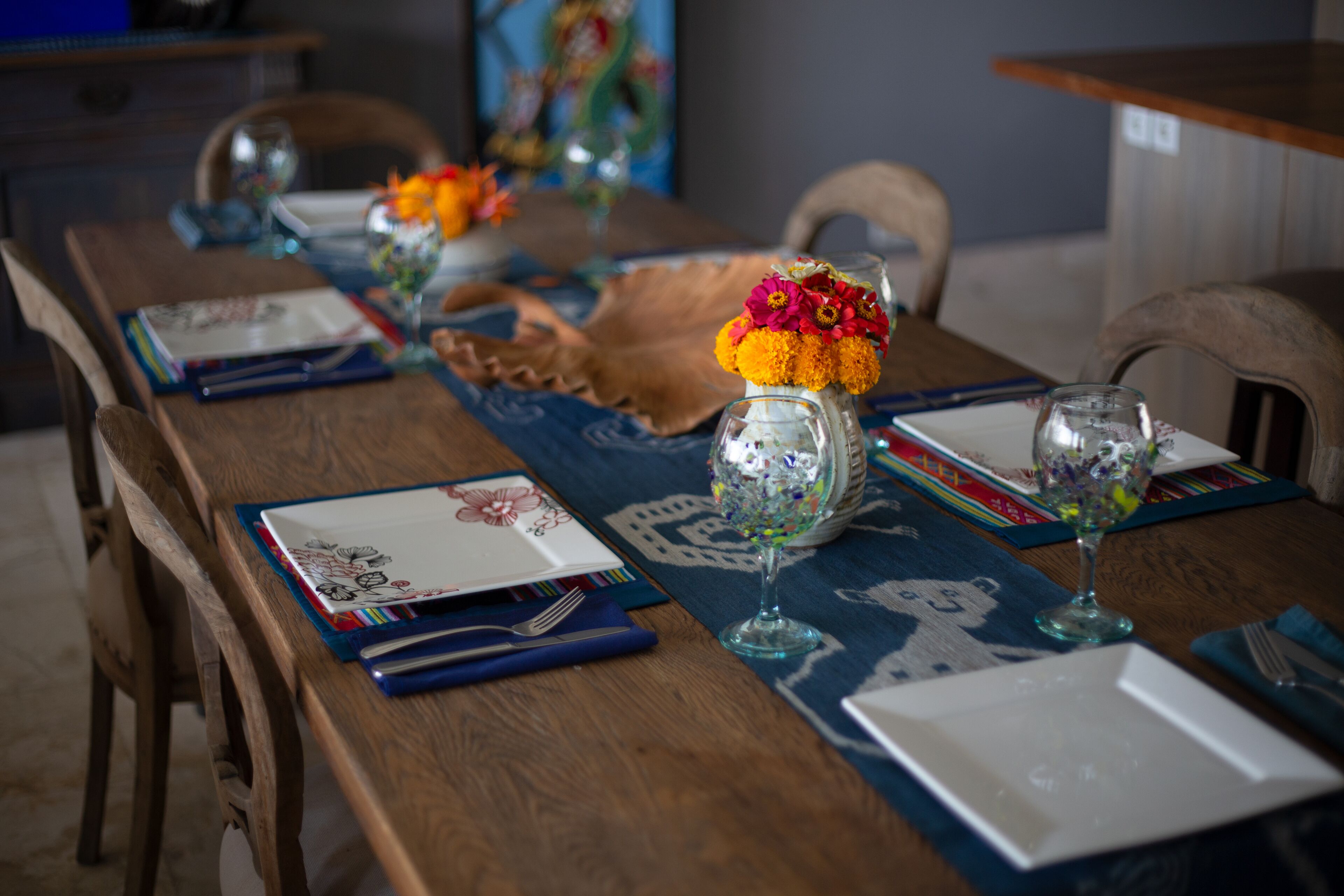 A dining table set with plates, glasses, and a vase of flowers.