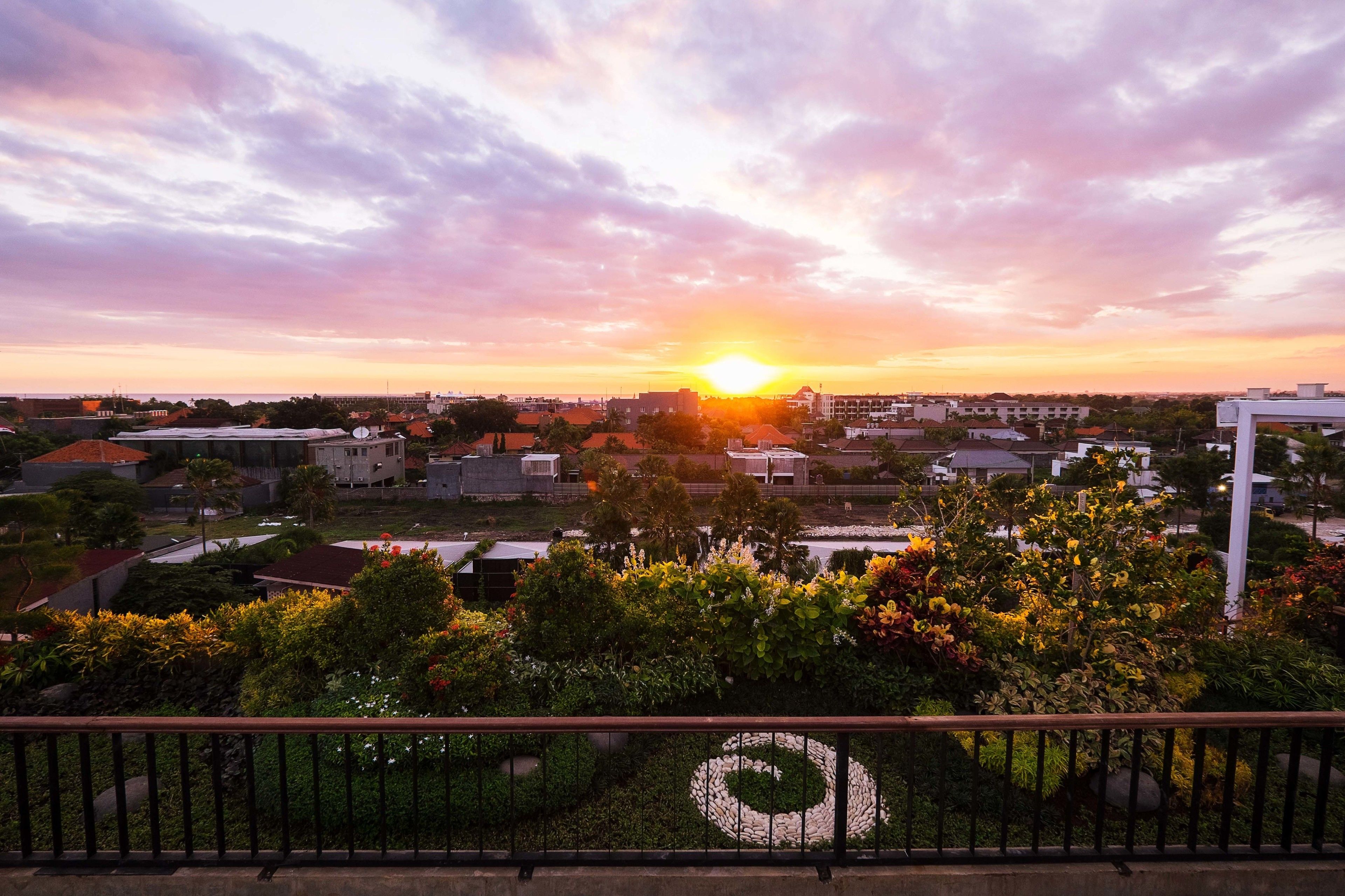 A sunset over a residential area with houses and greenery.