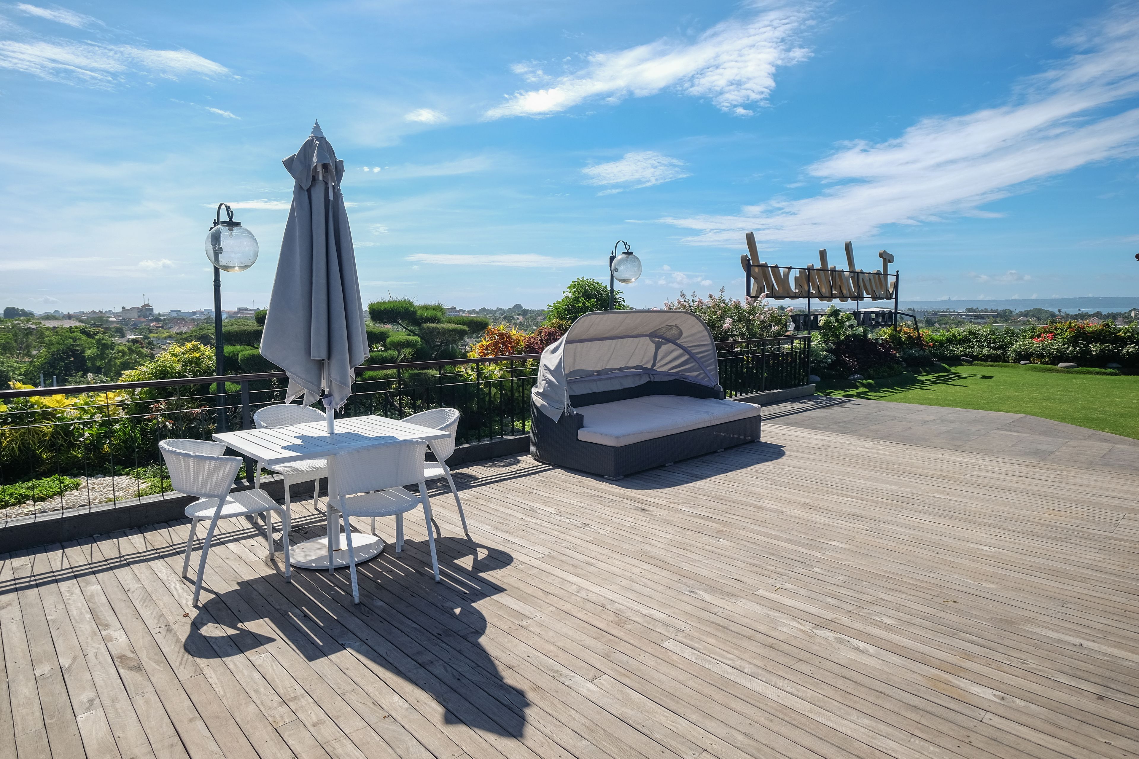 Una terraza de madera con mobiliario exterior, que incluye una mesa y sillas, y un área de descanso techada.