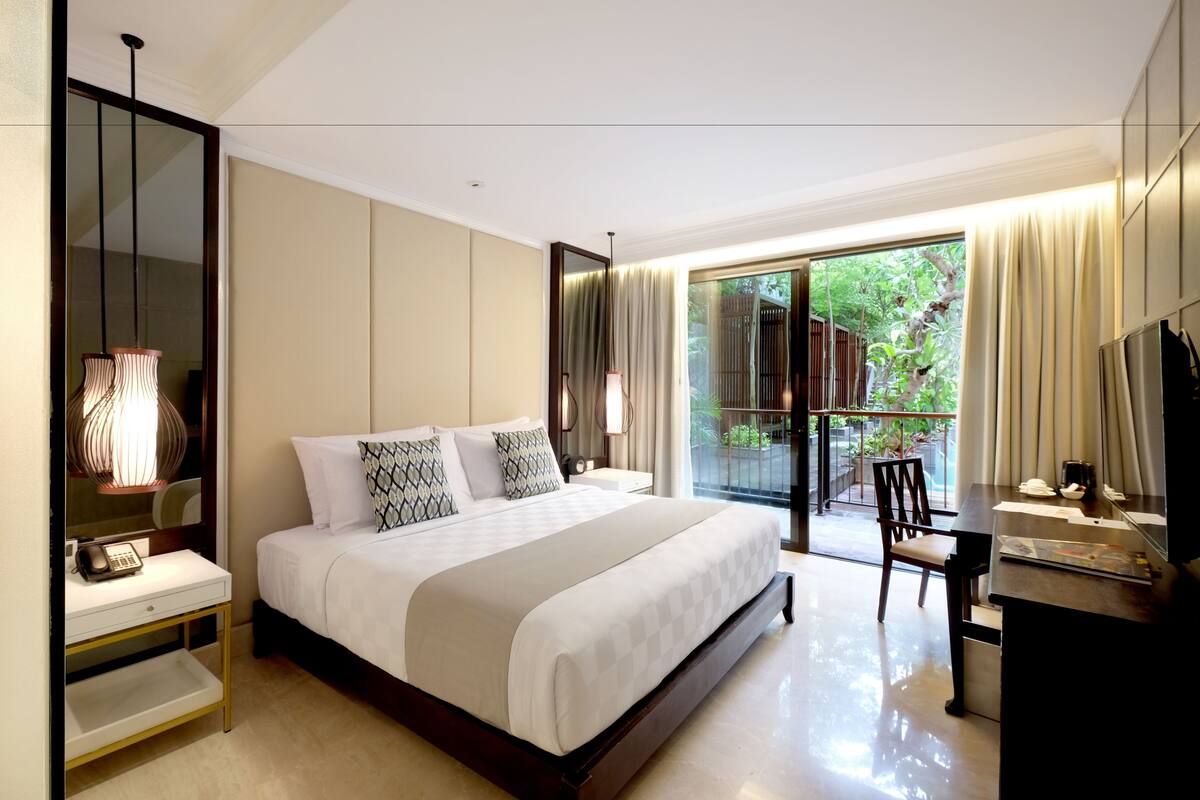 Una habitación de hotel moderna con una cama grande, una mesita de noche y un escritorio con una silla.