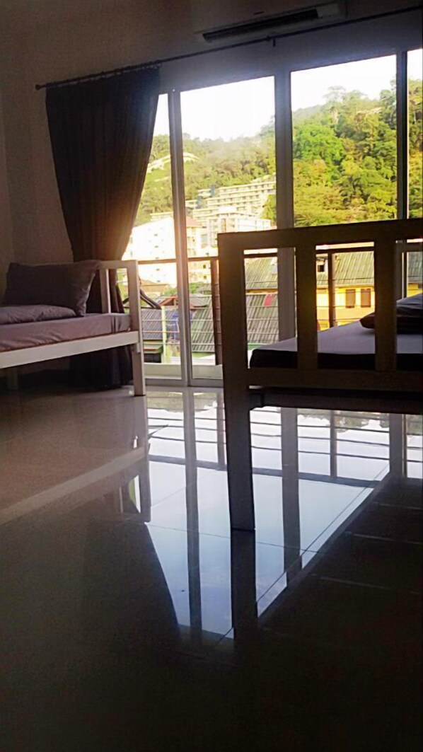 A room with a large window, a sofa, and a chair. - Bedbox Guesthouse & Hostel (Patong)