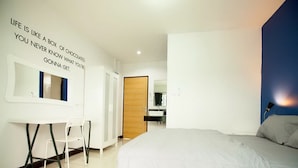 A modern bedroom with a bed, a desk, and a mirror. There is a motivational quote on the wall. - Bedbox Guesthouse & Hostel (Patong)