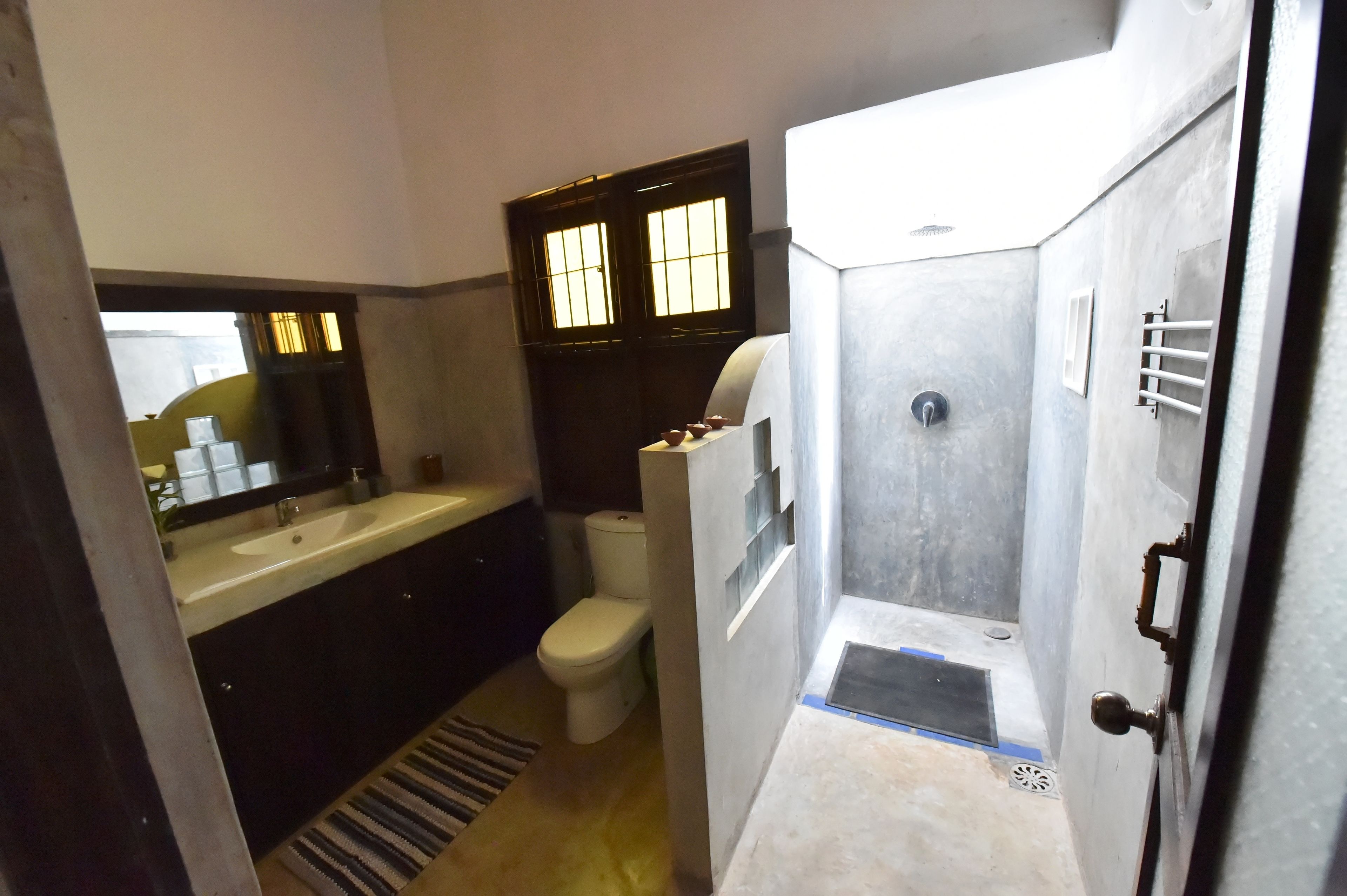 A compact bathroom with a sink, toilet, and shower.