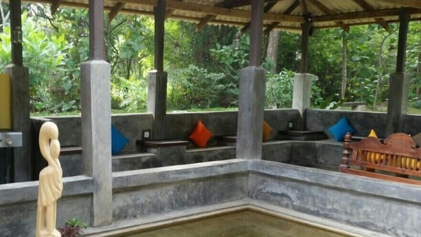Un jardin intérieur paisible, agrémenté d’un élément aquatique central, de bancs en pierre et d’une statue.