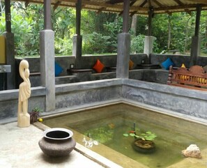 Un jardin intérieur paisible, agrémenté d’un élément aquatique central, de bancs en pierre et d’une statue.
