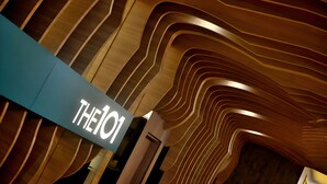 A modern interior with a unique wooden ceiling design and a sign reading "THE101".