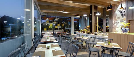 Un restaurante moderno con una barra larga, varias mesas y sillas.