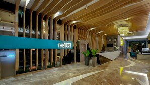 A modern lobby with a curved wooden ceiling, a reception desk, and a marble floor.
