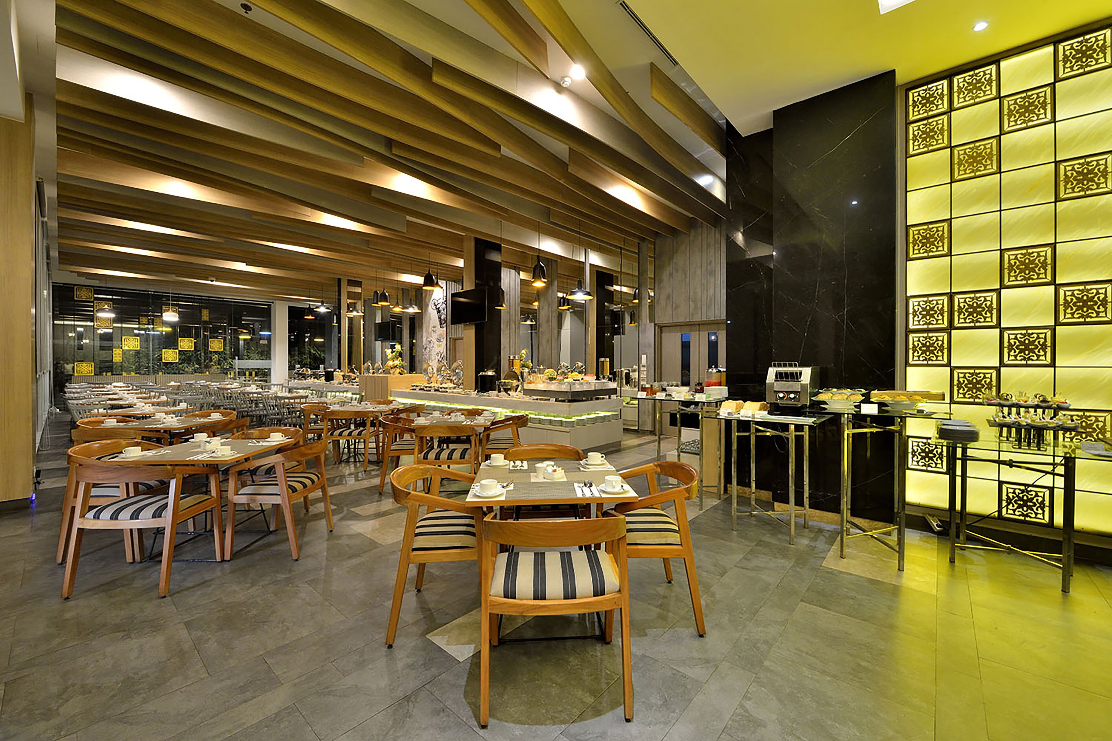 A spacious dining area with multiple tables and chairs, a central bar area, and a decorative wall with patterned tiles.
