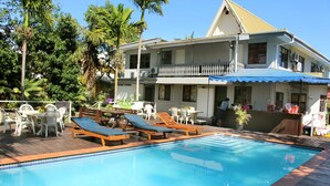 Une piscine avec des chaises longues et une terrasse en bois.