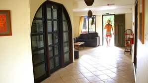 Un hall d’hôtel avec une grande porte en arc de cercle, un canapé, une petite table et un extincteur.