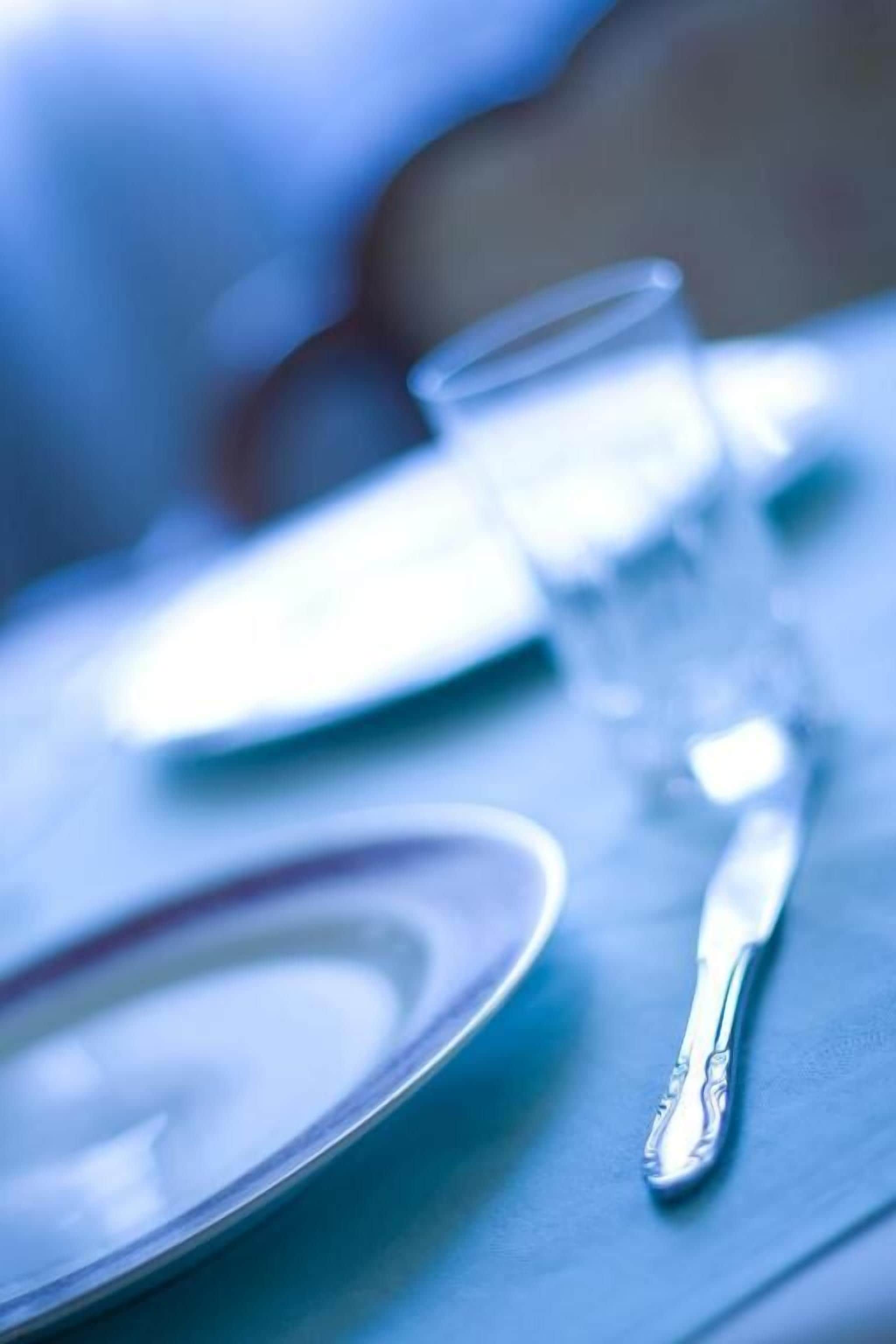 Close-up de uma mesa de jantar com um prato, um copo e uma faca.