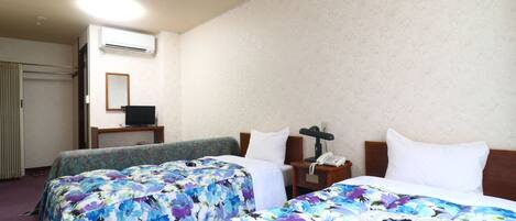 A hotel room with two beds, a desk with a computer, and a phone.