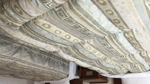 Una habitación con techo estampado y una cama con colchón y almohadas blancos.