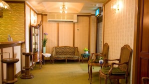 Un hall de hotel tradicional con un sofá, sillas, una recepción y una planta en maceta.