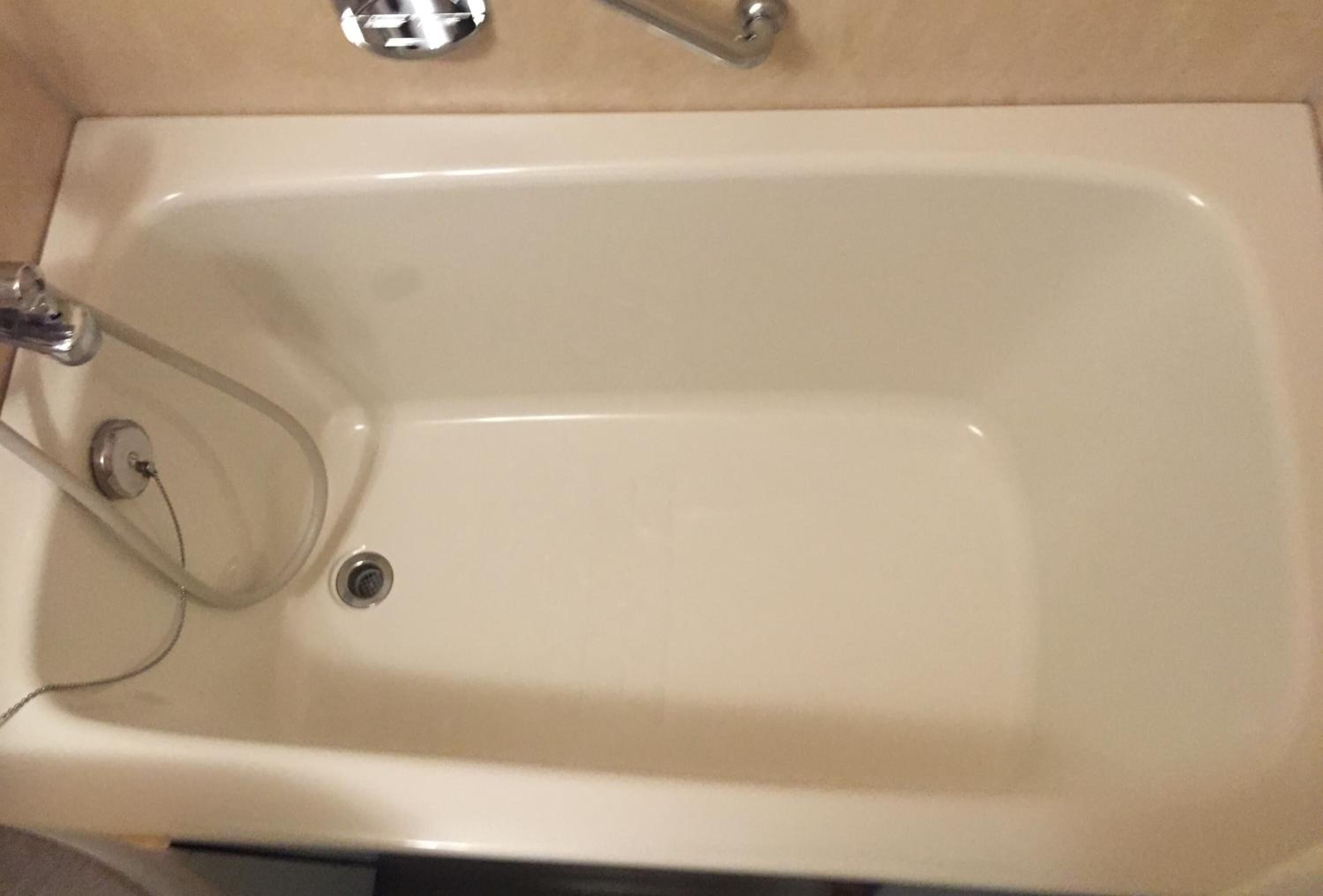 A white bathtub with a chrome faucet and a drain.