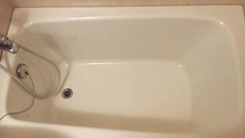 A white bathtub with a chrome faucet and a drain.