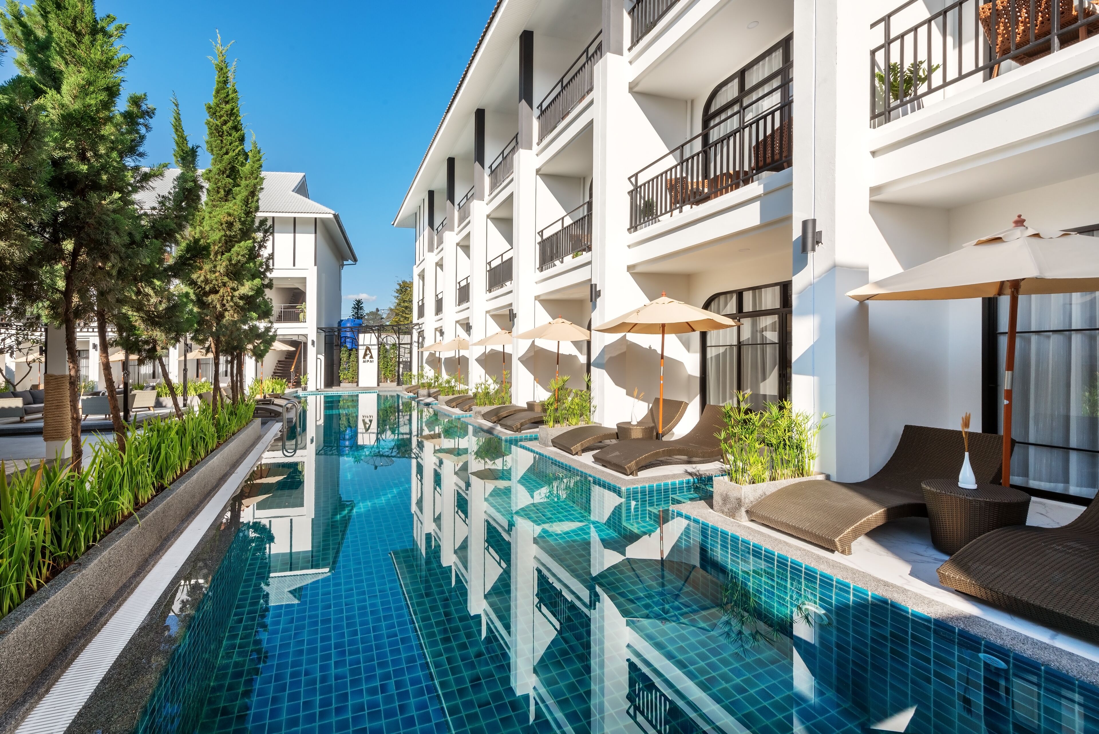 A modern hotel with a swimming pool, outdoor seating, and balconies.