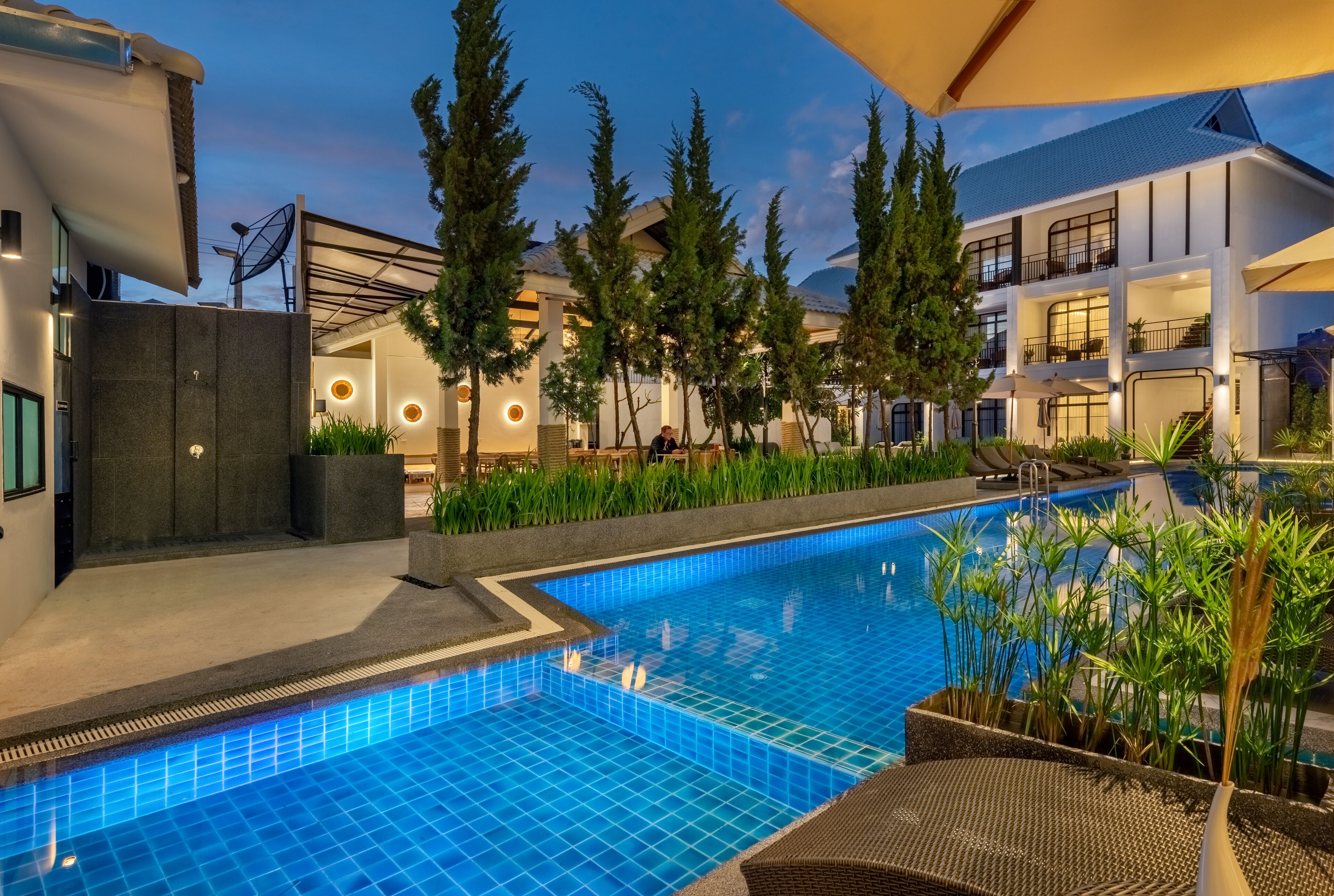 Ein modernes Hotel mit Schwimmbad, Sitzgelegenheiten im Freien und einem gepflegten Garten.