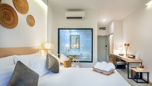 A modern hotel room with a large bed, a desk, and a view of the bathroom through a glass partition. - Ai Pai Hotel (Pai)