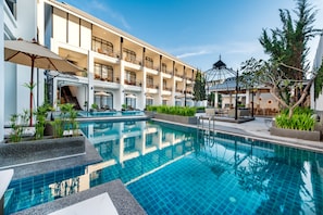 A hotel with a swimming pool, multiple balconies, and outdoor seating areas.