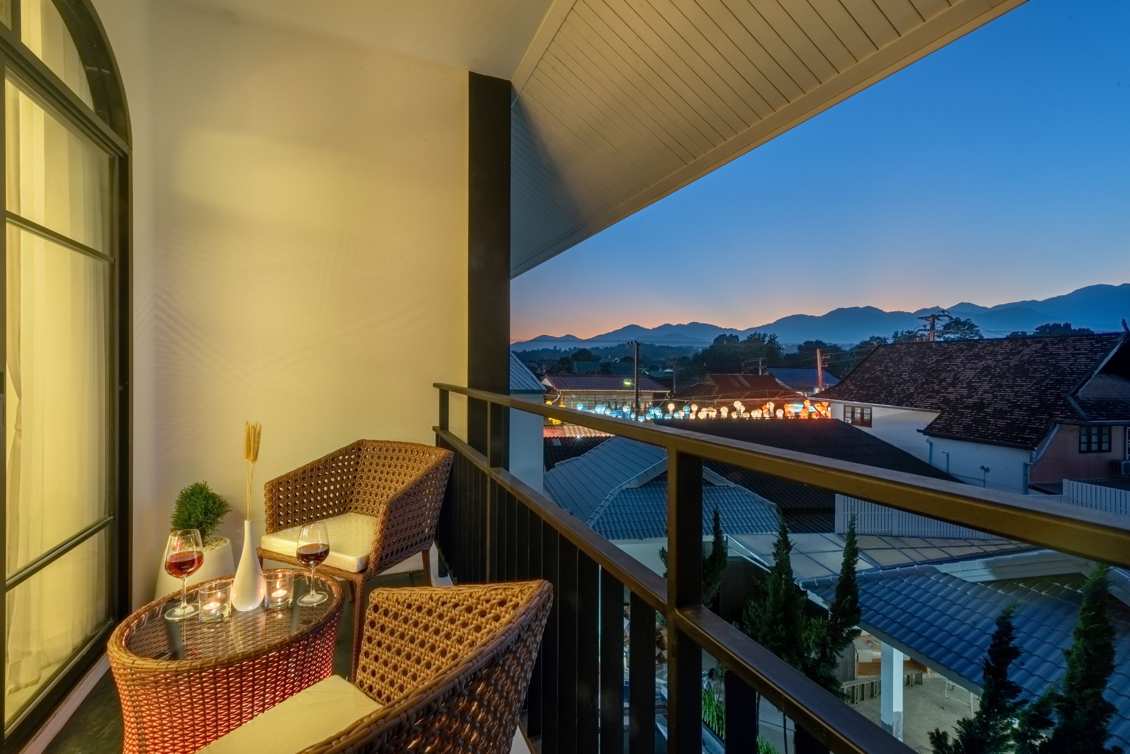 A balcony with wicker furniture, a vase, and wine glasses.