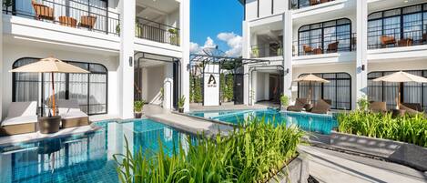 A modern hotel with multiple balconies, outdoor seating, and a swimming pool.