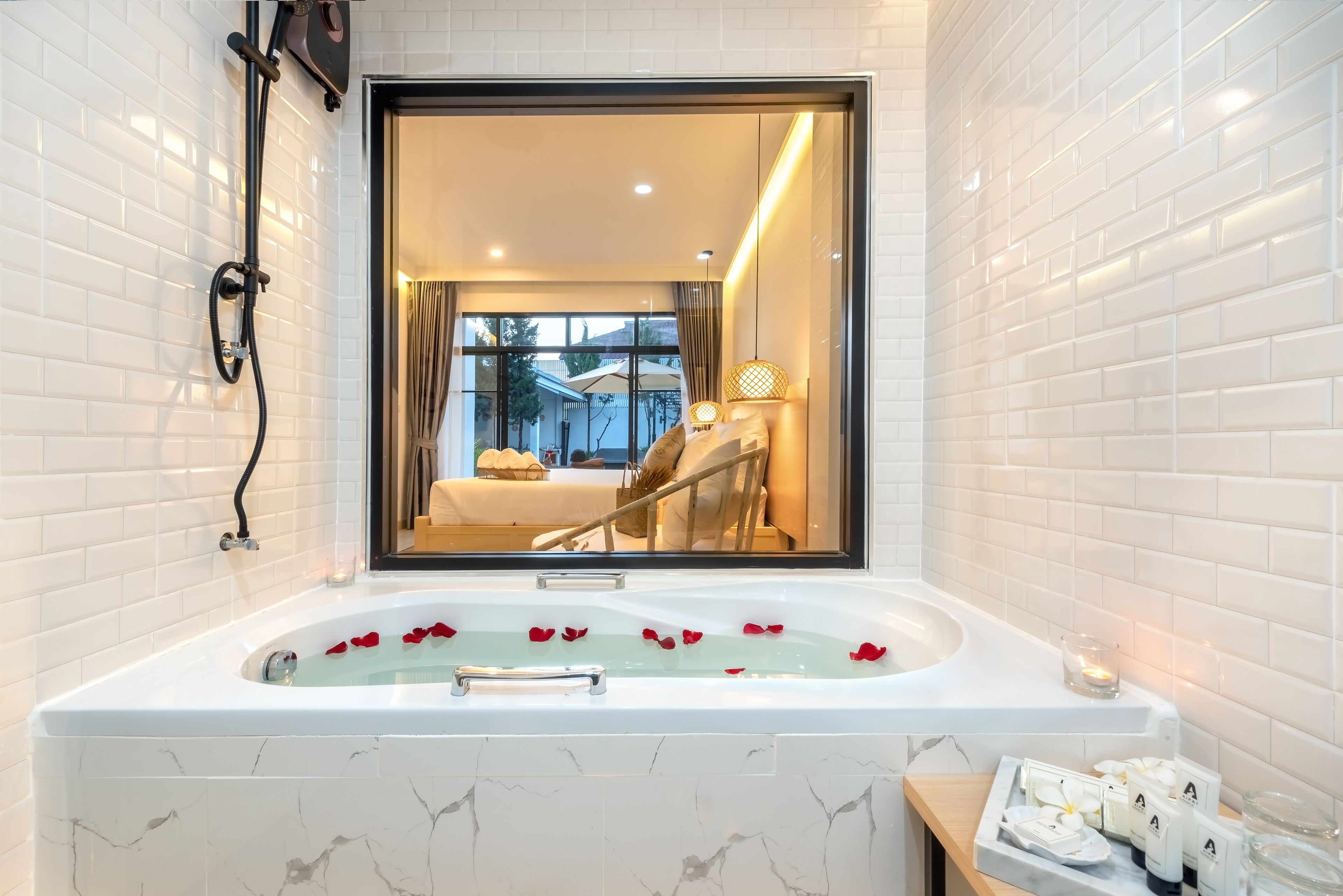 A modern bathroom with a large bathtub, a mirror, and a view of a bedroom.