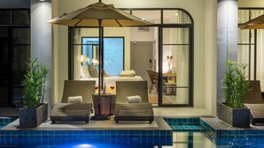 A poolside area with two wicker lounge chairs, a table, and an umbrella. - Ai Pai Hotel (Pai)