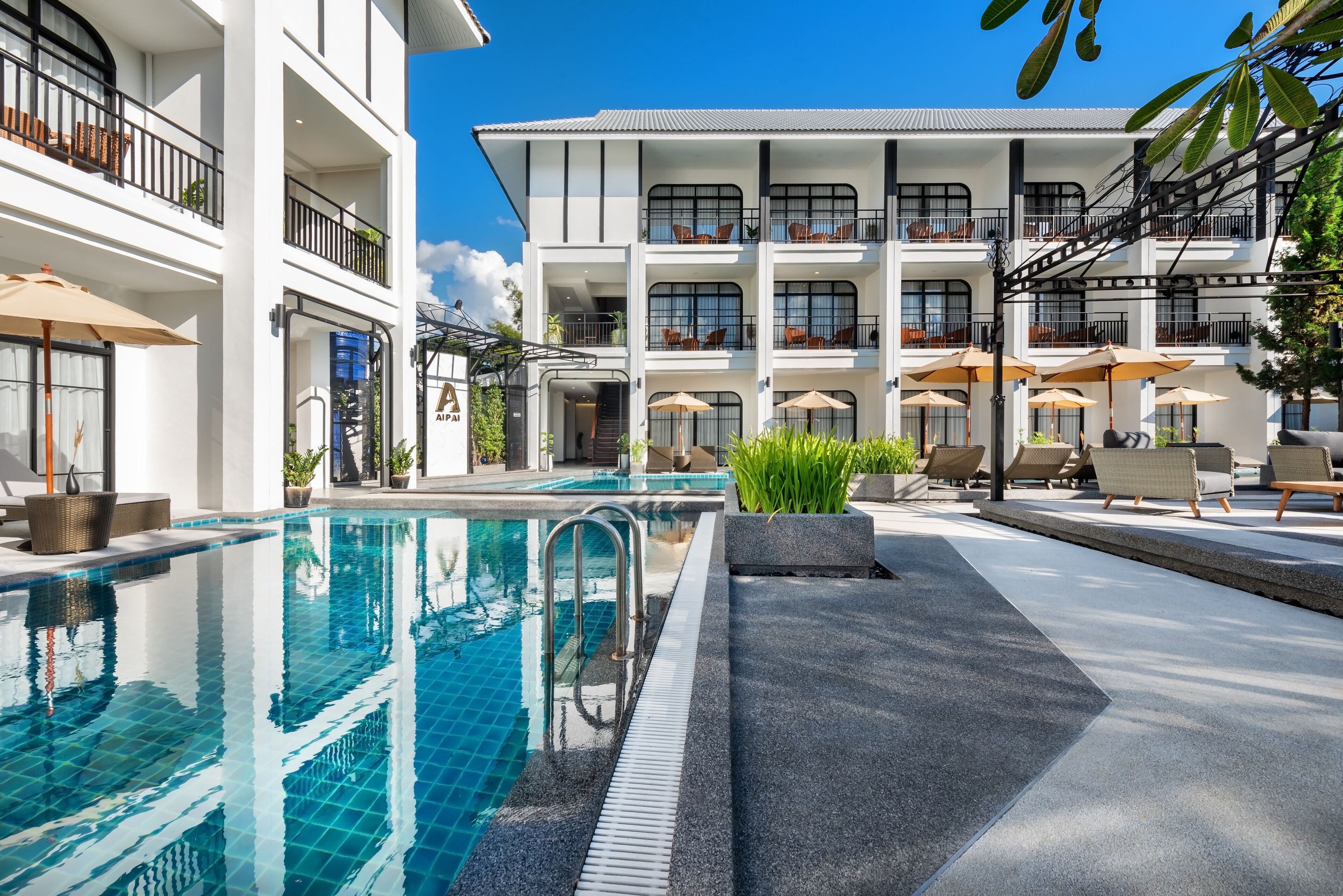 Un hôtel moderne doté d’une piscine, d’un espace extérieur aménagé et de plusieurs balcons.