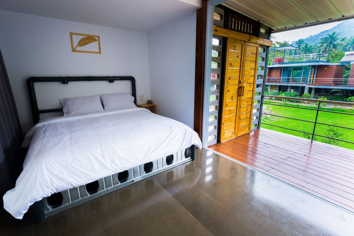 Un dormitorio con una cama, una puerta de madera y vistas a un paisaje verde.