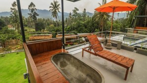 A wooden deck with lounge chairs and a hot tub, overlooking a lush garden and mountains. - Baan Boom Boxes (Koh Samui)