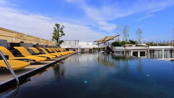 A swimming pool with yellow lounge chairs and a modern building in the background.