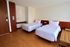 A hotel room with two single beds, a wooden floor, a wooden headboard, and a small seating area with a cushioned bench. - Varinah Resort (Sam Roi Yot)
