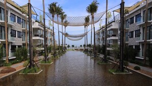 A hotel with a water feature in the center, surrounded by palm trees and modern buildings. - Varinah Resort (Sam Roi Yot)