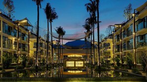 A hotel with multiple floors, a central atrium, and a pool area surrounded by palm trees. - Varinah Resort (Sam Roi Yot)