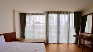 A hotel room with a large bed, a bench, a desk, and a sliding glass door to the outside. - Varinah Resort (Sam Roi Yot)