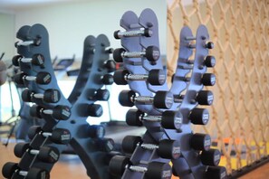 A gym with multiple rows of dumbbells on racks. - Varinah Resort (Sam Roi Yot)