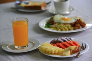 A breakfast setting with plates of food, a glass of orange juice, and a cup of coffee. - The Floral Breeze Wun Zin Hotel (Meiktila)