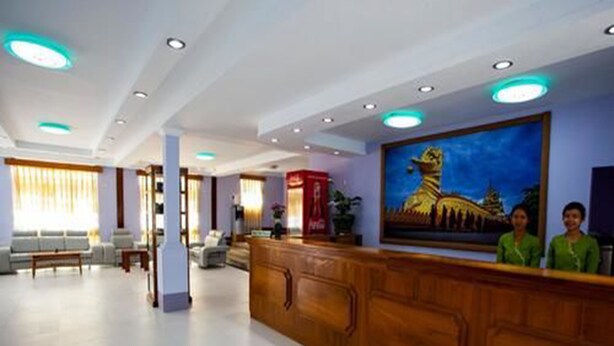 En hotellobby med en receptionsdisk i trä, en stor målning som föreställer ett tempel och en sittgrupp med soffor och ett soffbord.