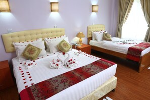 A hotel room with two beds, each with a headboard, bedside tables, and lamps. - The Floral Breeze Wun Zin Hotel (Meiktila)