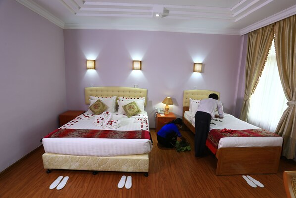 A hotel room with two beds, a wooden floor, and a large window with curtains. - The Floral Breeze Wun Zin Hotel (Meiktila)