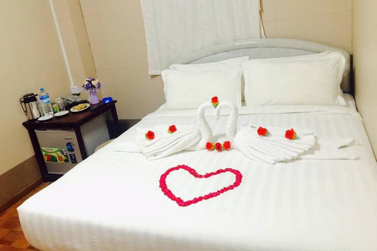 A hotel room with a neatly made bed, a bedside table with toiletries, and a window with curtains.