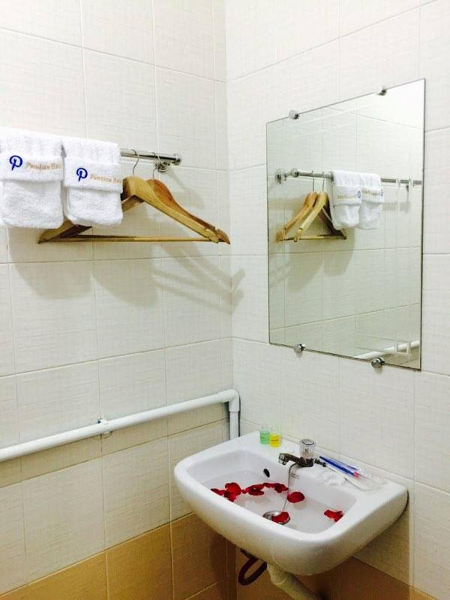 Un baño con lavamanos, espejo, toallero y barandilla.