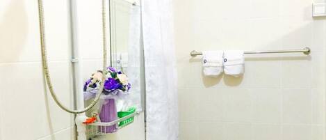 Un baño con ducha, lavamanos y un perchero para toallas.