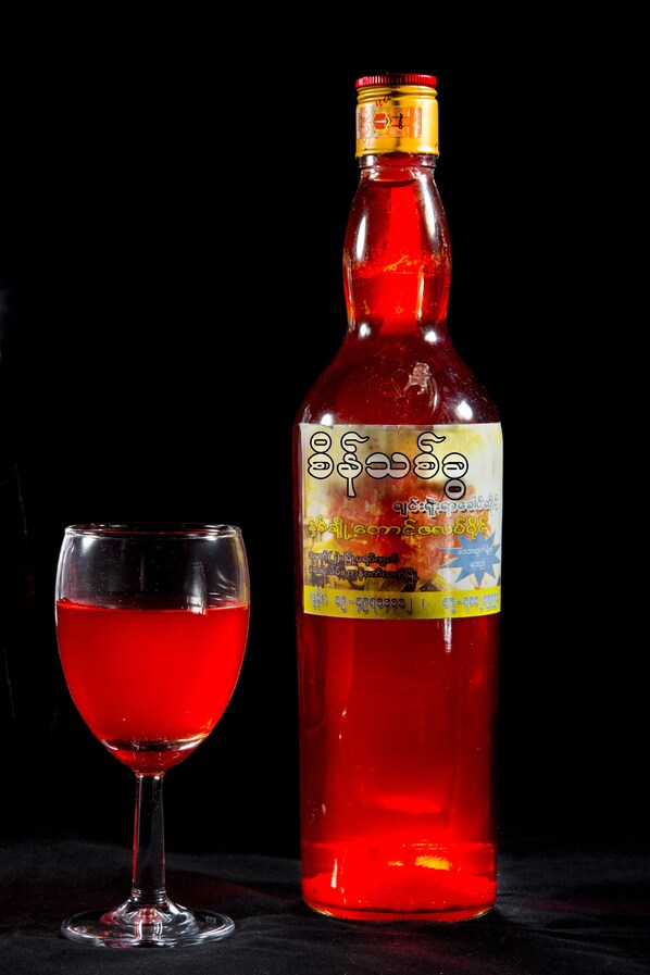 A bottle of red liquid next to a glass filled with the same liquid. - The Floral Breeze Hotel Mt.Victoria (Kanpetlet)