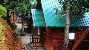 Una cabaña de madera con techo metálico, un camino de piedra y una terraza de madera.