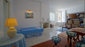 Una habitación con cama, mesa, lámpara, chimenea y sofá.